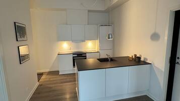Une cuisine moderne avec des meubles blancs, un îlot central et un four encastré.