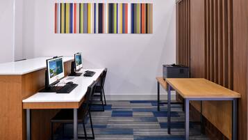 A modern office space with a white desk, two computer monitors, a keyboard, and a chair. There is a wooden panel wall and a blue and gray striped carpet.