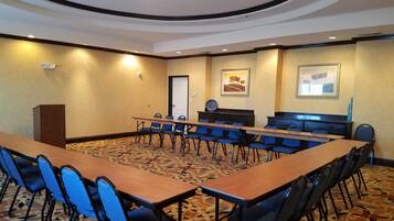 A conference room with a long table, chairs, a podium, and framed artwork on the walls.