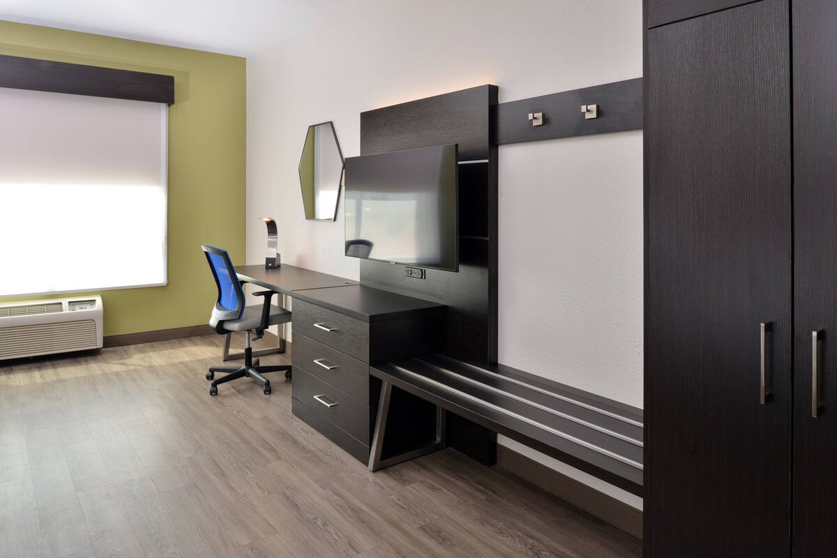 Un espace de bureau moderne comprenant un bureau, une chaise et un grand téléviseur à écran plat fixé au mur.