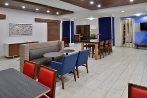 Eine moderne Hotelhalle mit einer Couch, einem Essbereich und einem an der Wand montierten Fernseher.