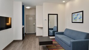 Una sala moderna con un sofá azul, una mesita negra y un tapete colorido a rayas.