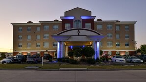A multi-story hotel with a prominent entrance, parking lot, and a well-lit facade.