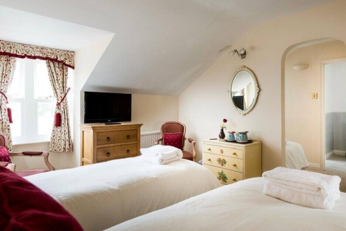 Une chambre d’hôtel avec deux lits, une télévision, une commode, une chaise et un miroir.