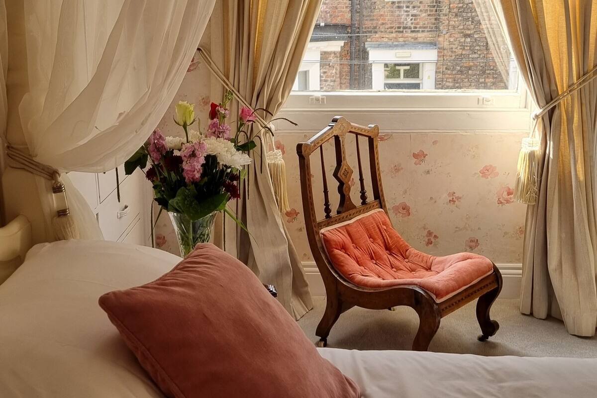 Une chambre à coucher avec un lit, une chaise et une fenêtre avec des rideaux.