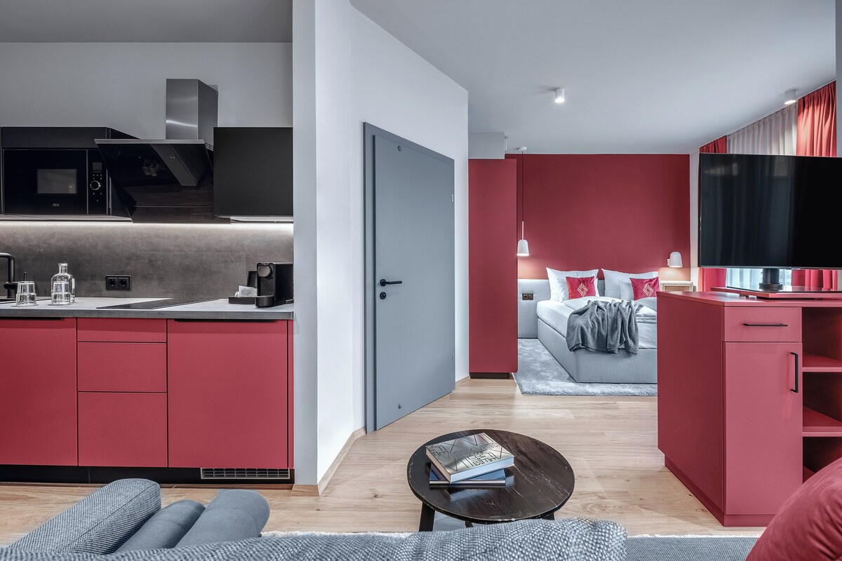 Un espacio habitable moderno con cocina, sofá, mesa de centro y televisor.