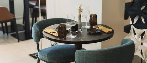 A dining area with a round table, two upholstered chairs, a lamp, and a decorative wall piece.