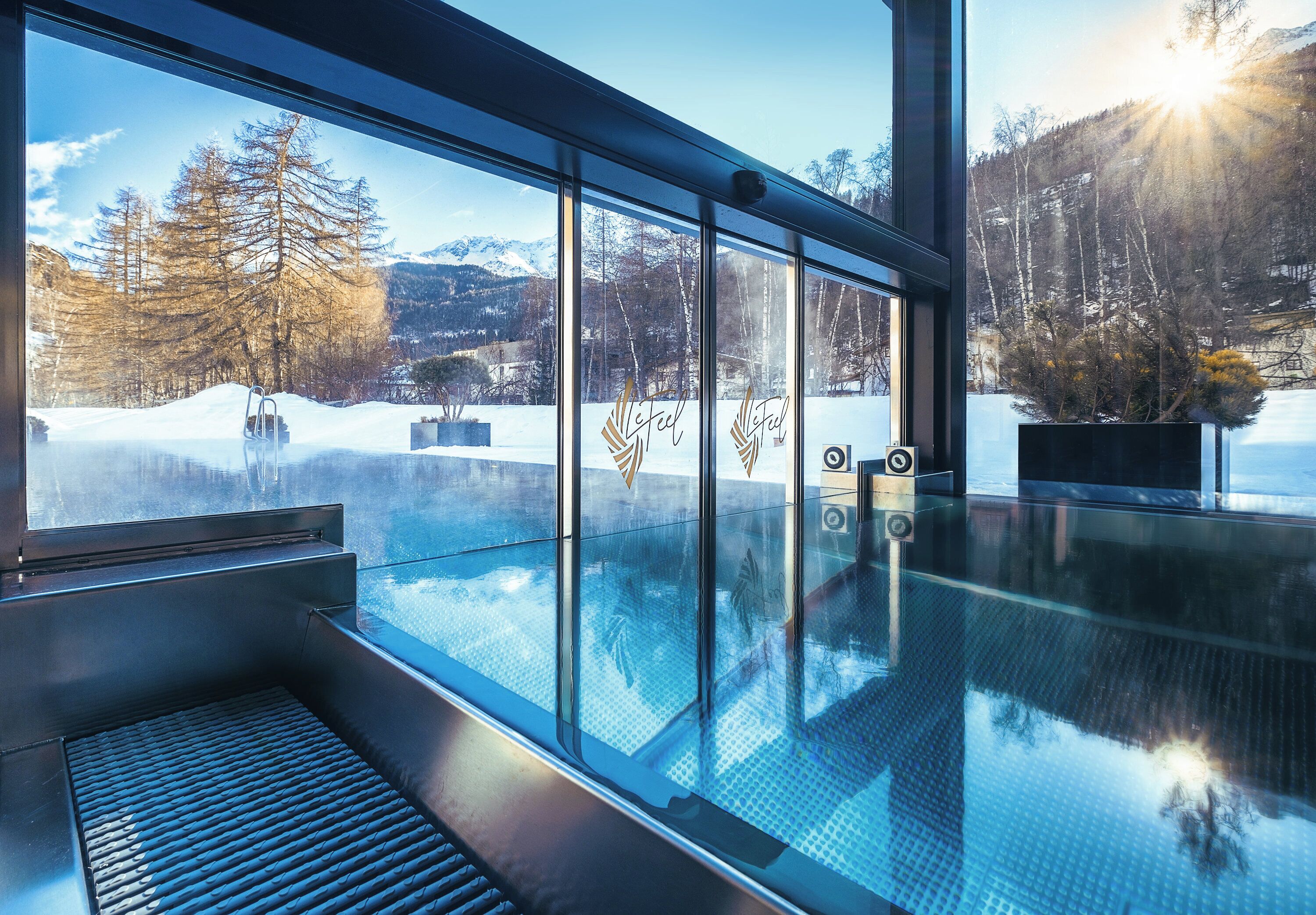 Una piscina techada, una piscina al aire libre, sombrillas