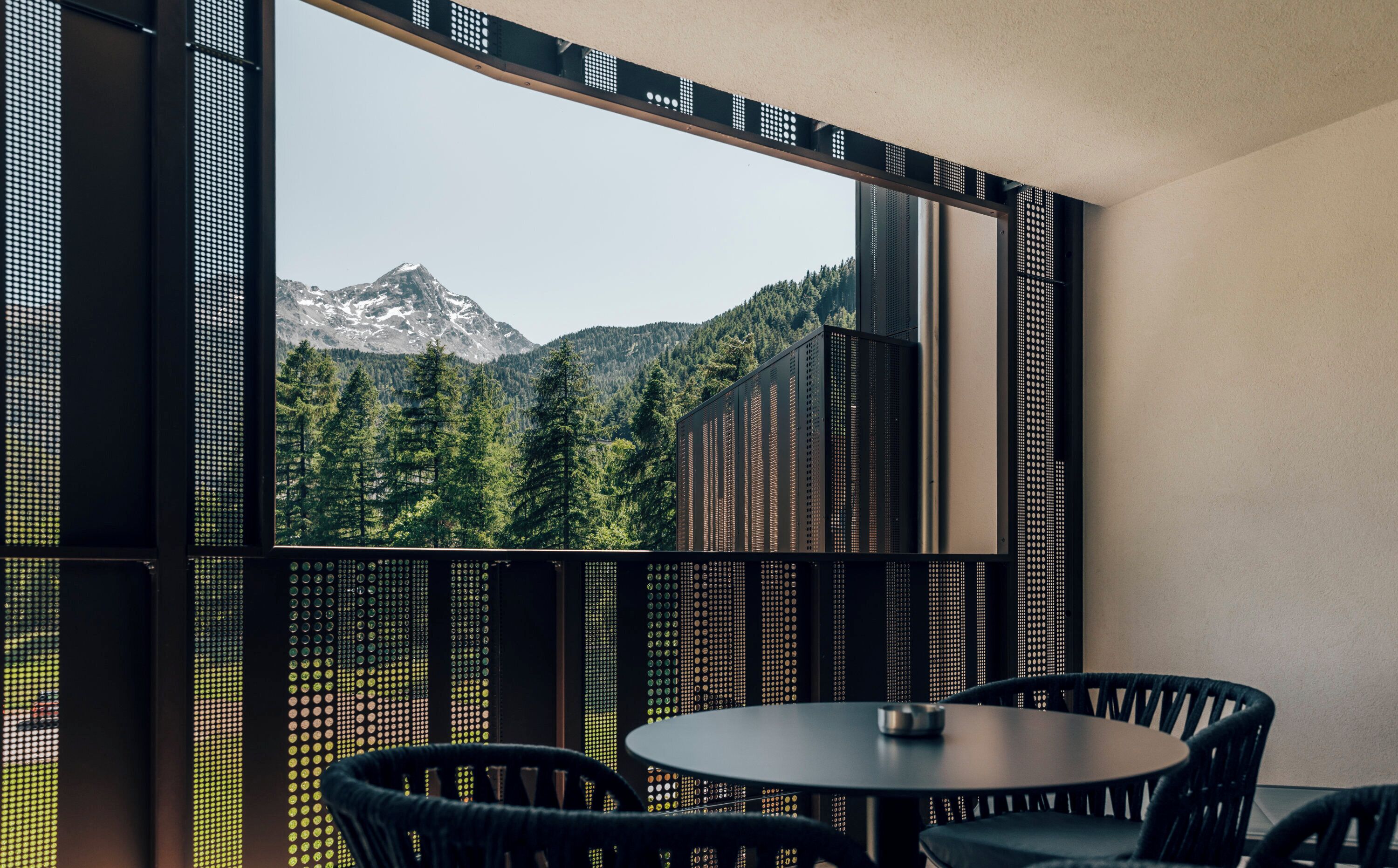 Una habitación moderna con un ventanal grande con vistas a un paisaje montañoso.