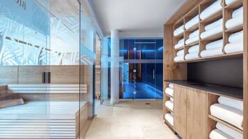Un moderno vestíbulo de hotel con un muro de cristal, asientos de madera y una gran estantería de madera con toallas.