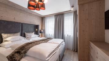 Ein modernes Schlafzimmer mit einem großen Bett, Holzwandverkleidung, einem Fellüberwurf und einer Deckenleuchte.
