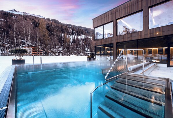 Una piscina techada, una piscina al aire libre, sombrillas