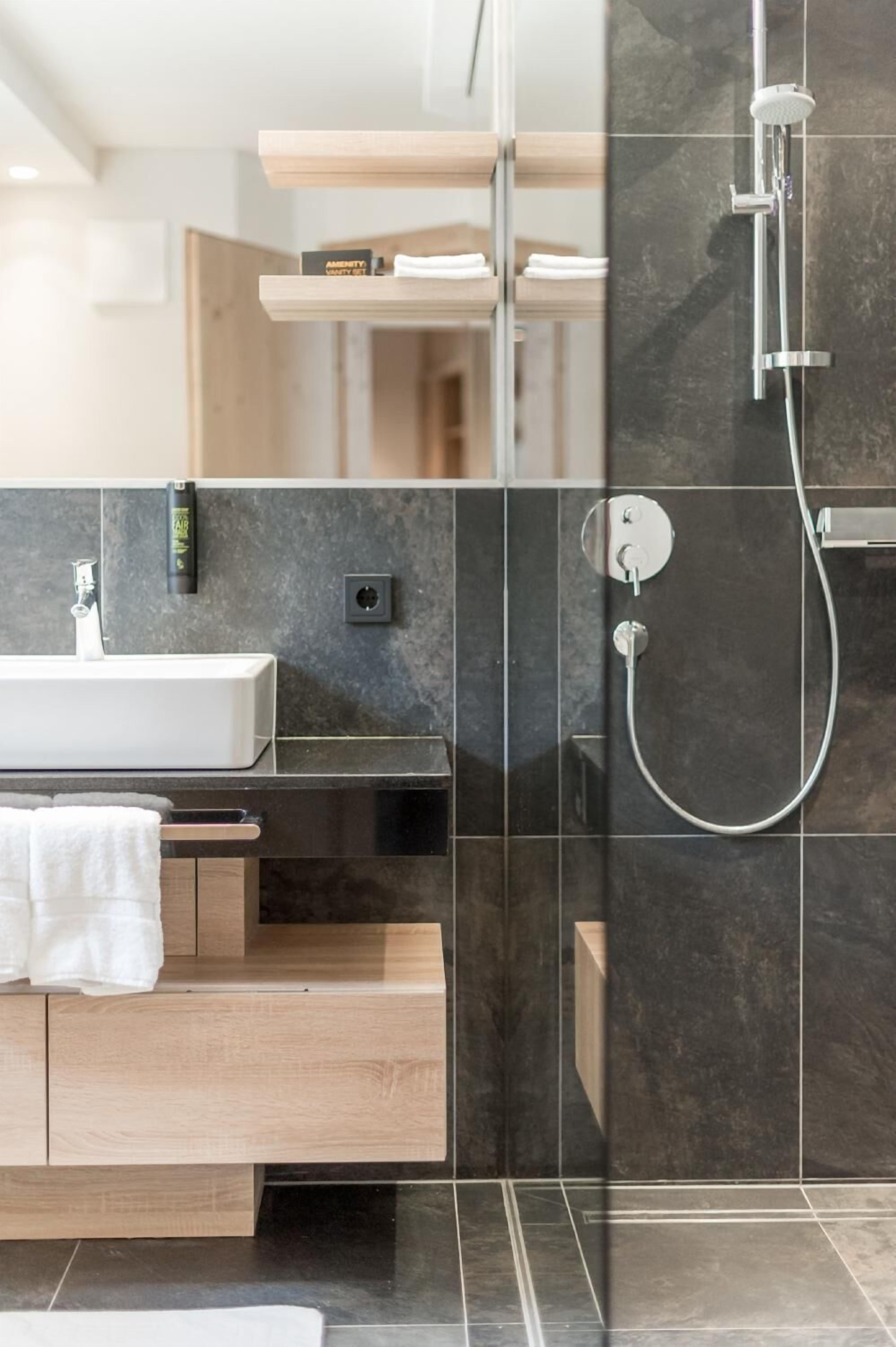 A modern bathroom with a glass-enclosed shower, a wooden vanity, and a white sink.