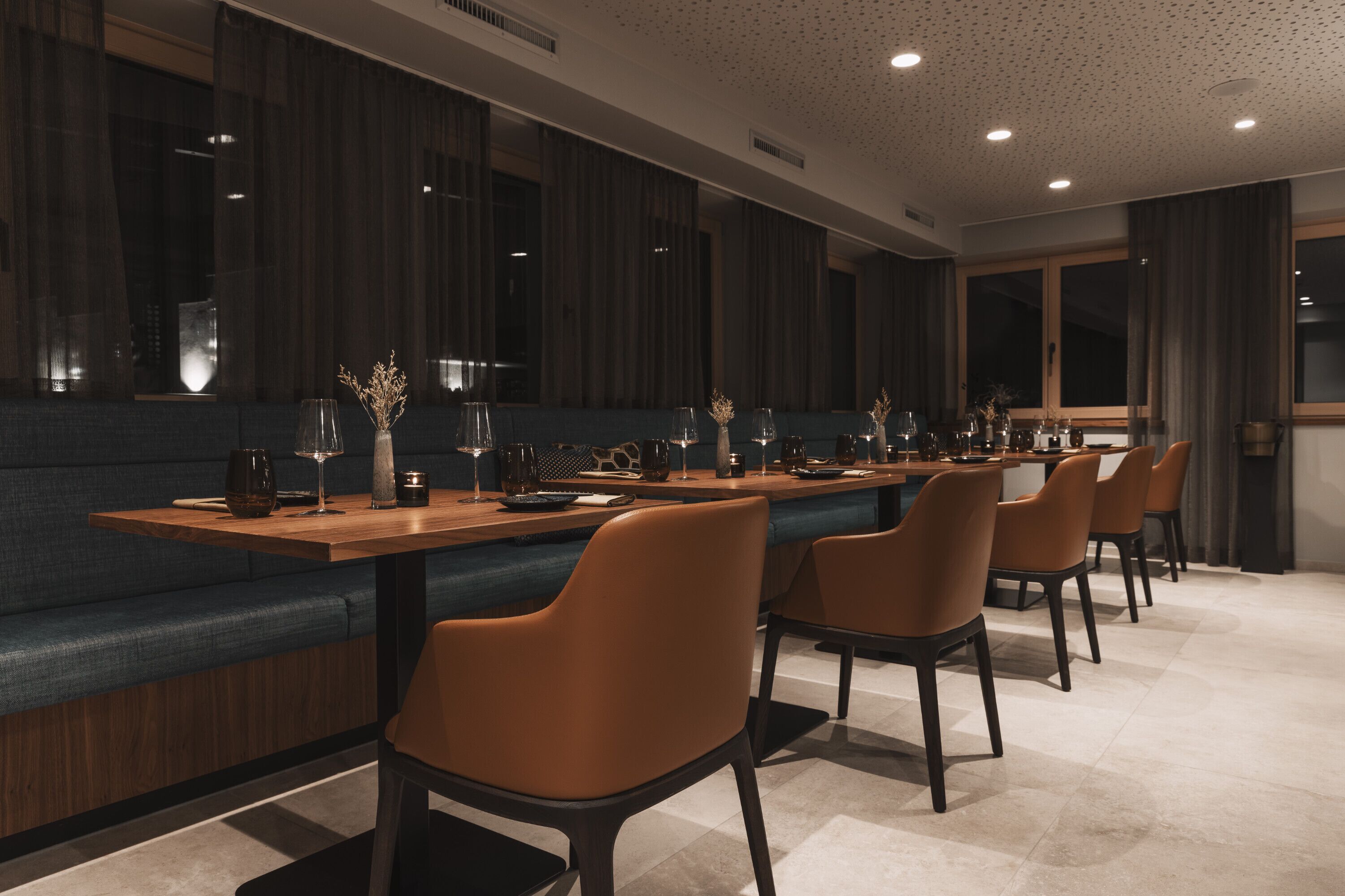 A modern dining area with a long table, multiple chairs, and a cushioned bench.