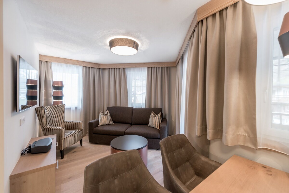 Una sala moderna con un sofá, sillones, una mesita de centro y un televisor.