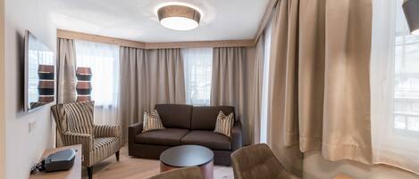 A modern living room with a sofa, armchairs, a coffee table, and a TV.