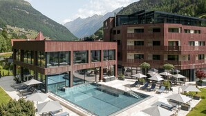 A modern hotel with a pool, outdoor seating, and mountain views. - AlpenParks The Secret Sölden (Soelden)