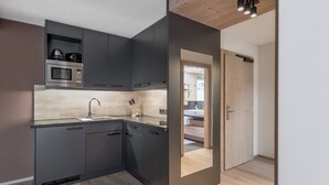 A modern kitchen with dark cabinetry, a built-in microwave, and a sink. - AlpenParks The Secret Sölden (Soelden)