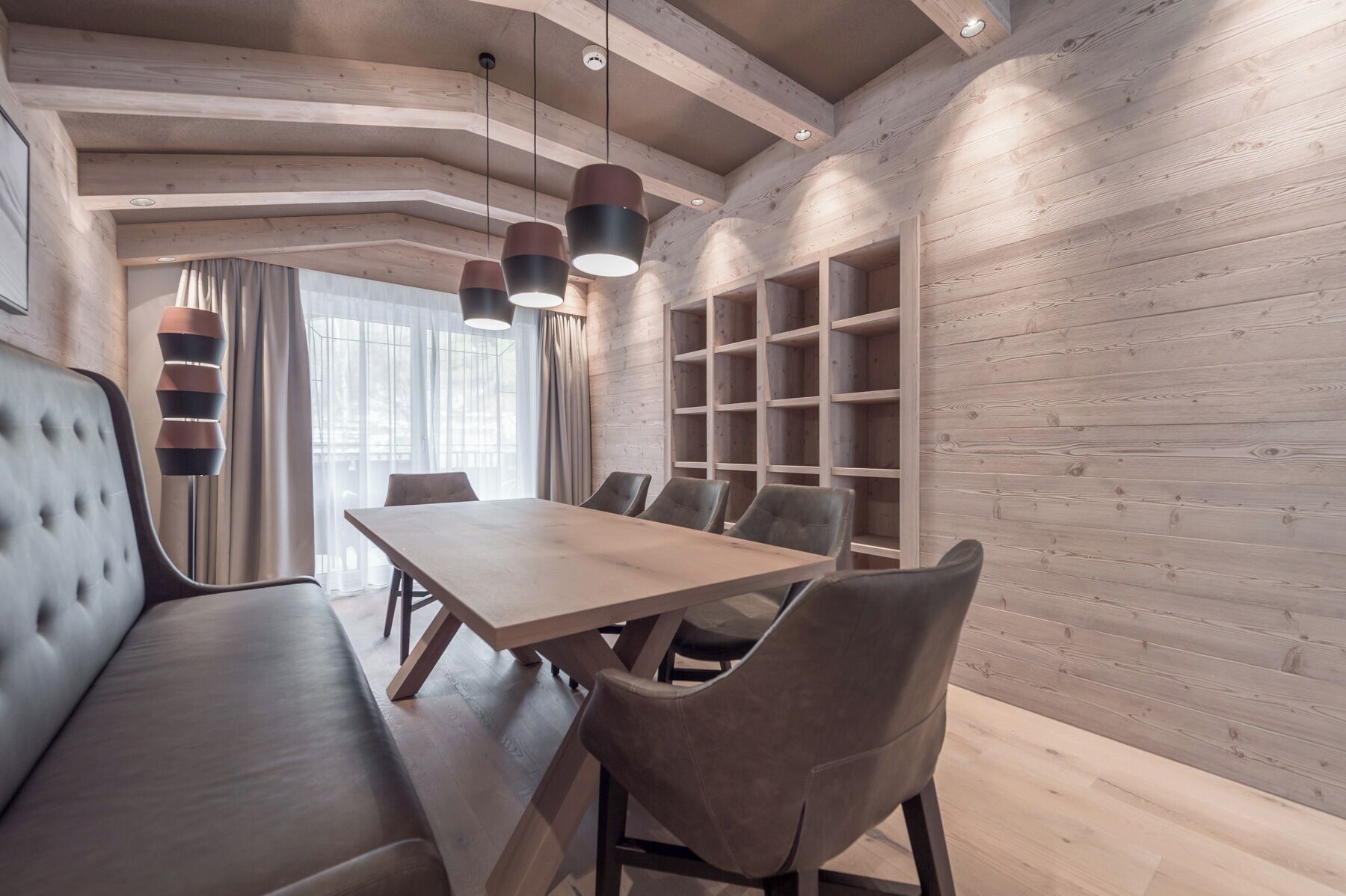 Ein modernes Interieur mit einer Holzwand, einem Esstisch, Stühlen und einer Couch.