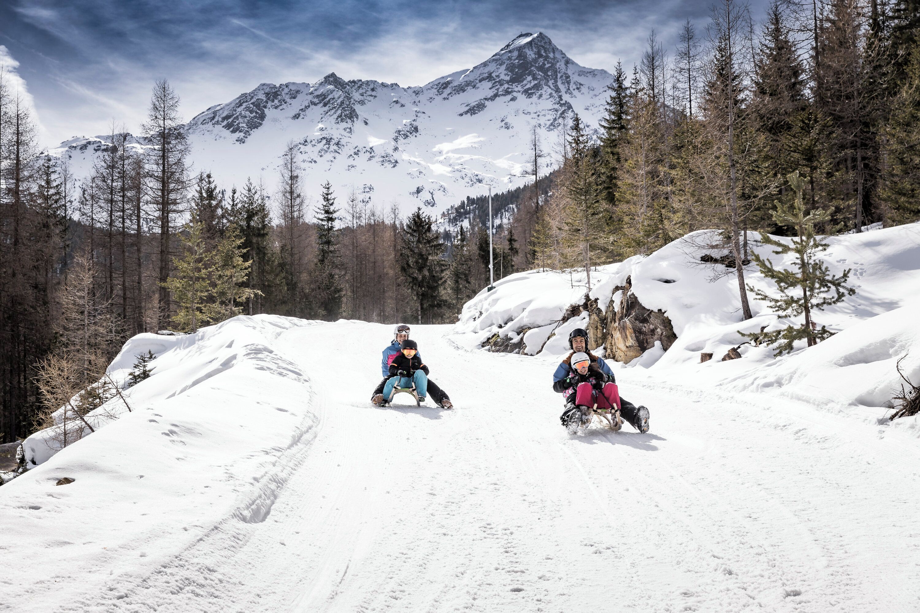 A snowy mountain path with two people sledding.