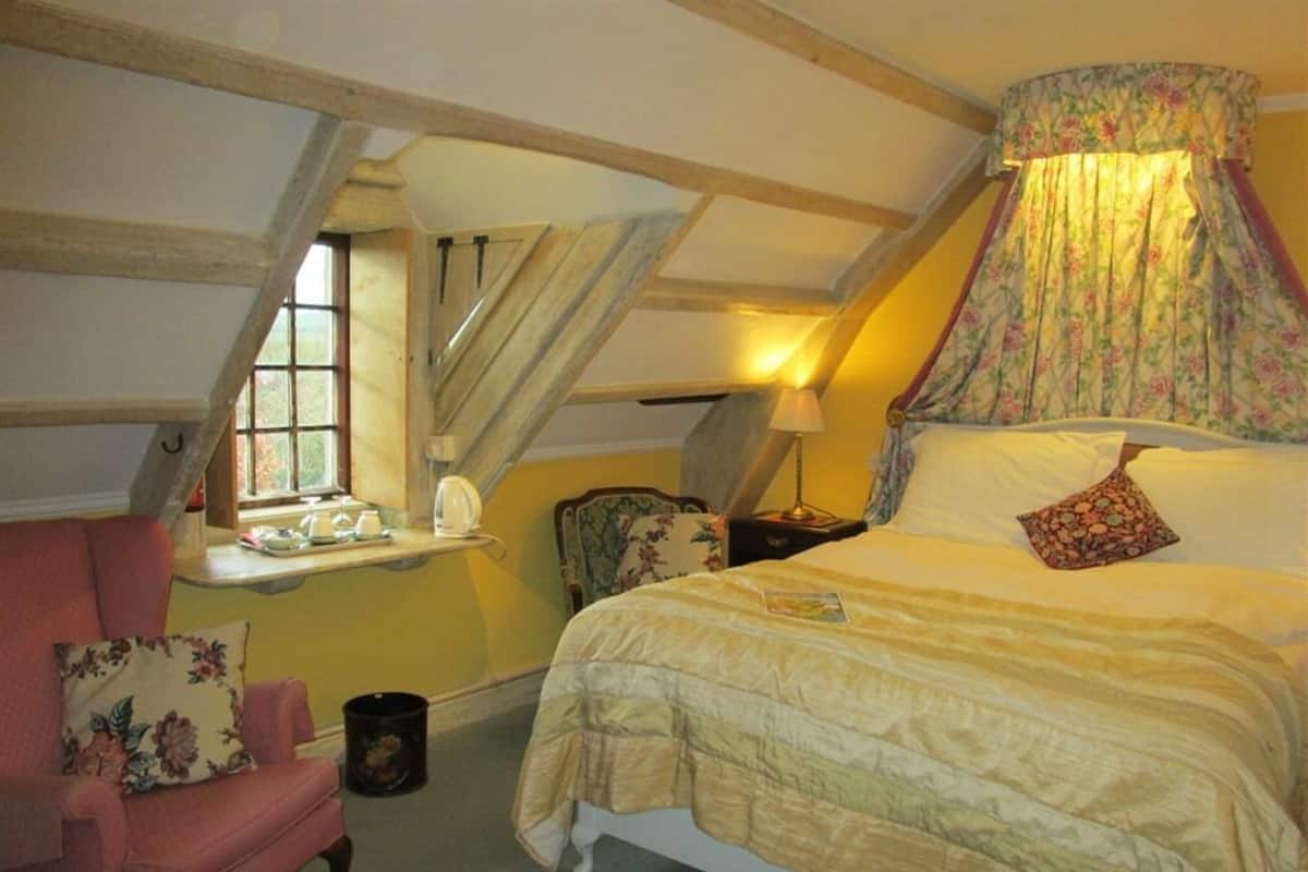 Quarto com cama, cadeira, luminária e janela.