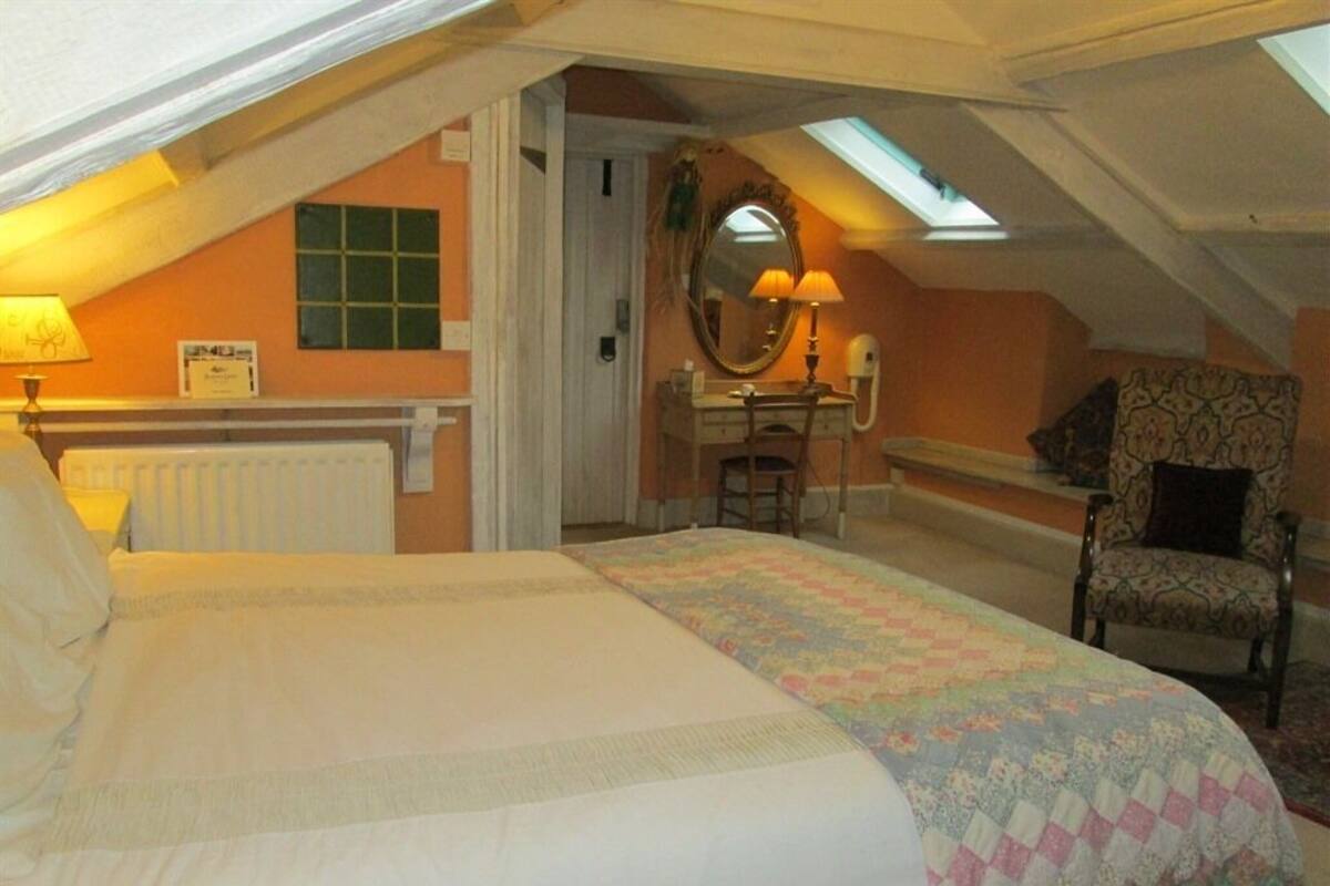 Um quarto com cama, escrivaninha, cadeira e claraboia.