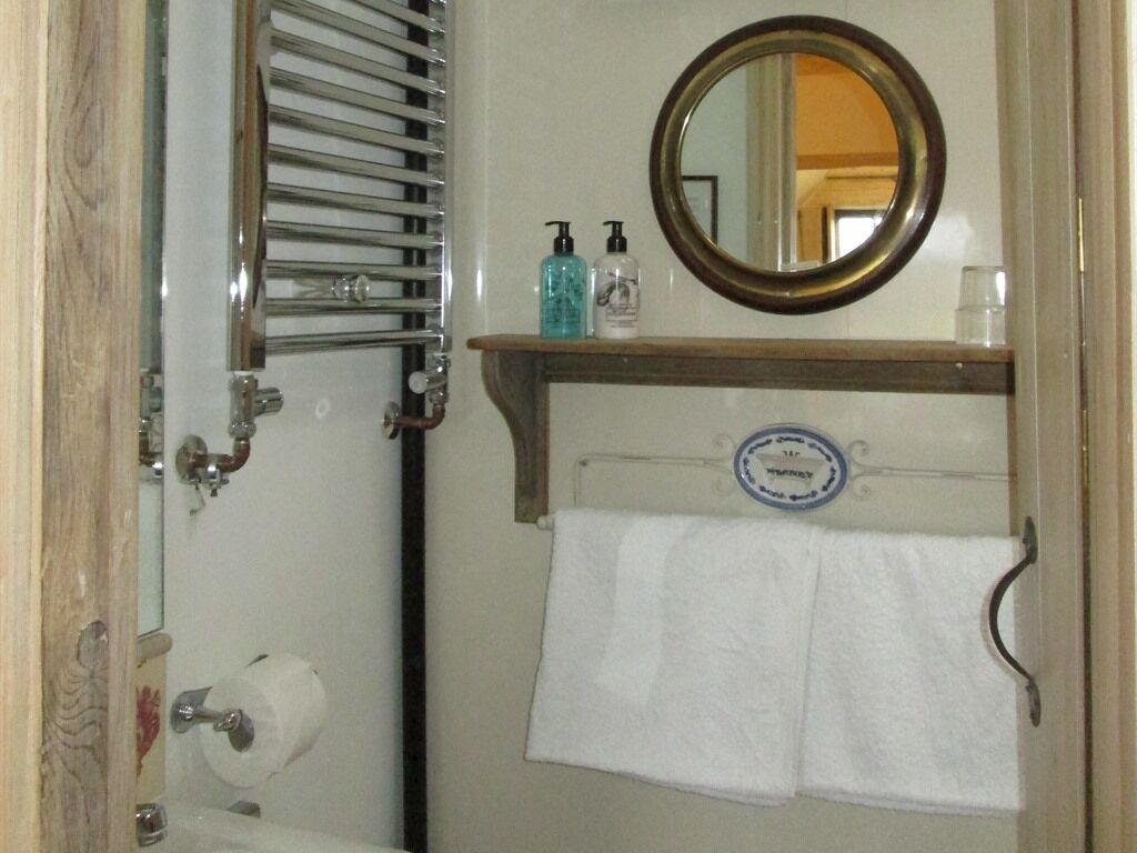 A bathroom with a towel rack, a mirror, and toiletries on a shelf.