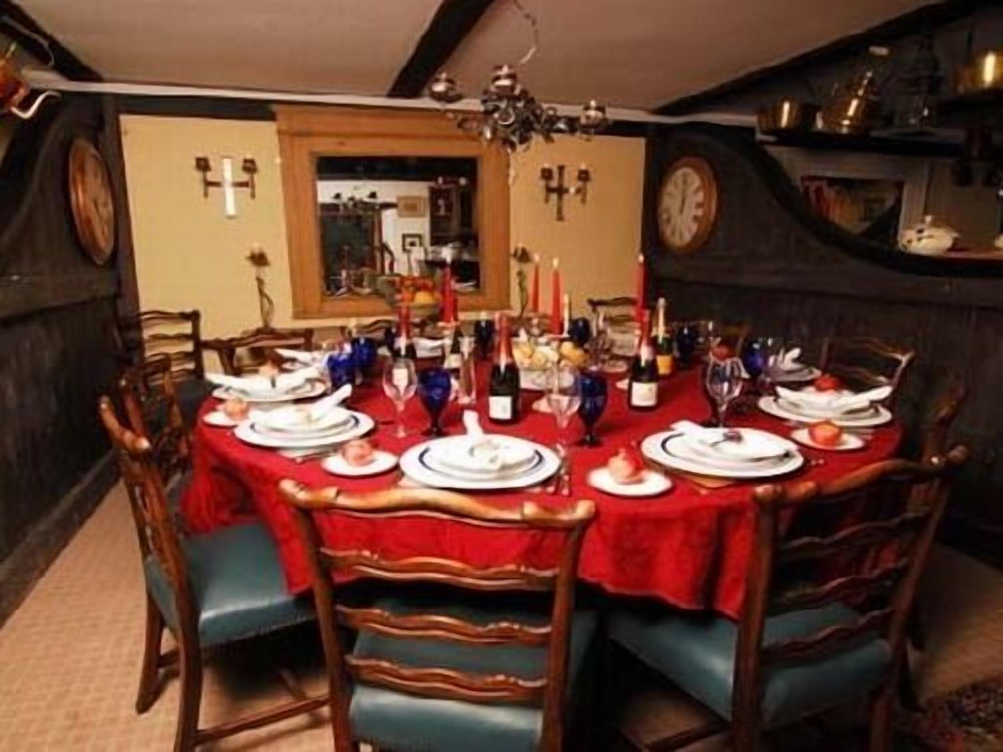 A dining room with a round table set for six, surrounded by wooden chairs with blue upholstery.