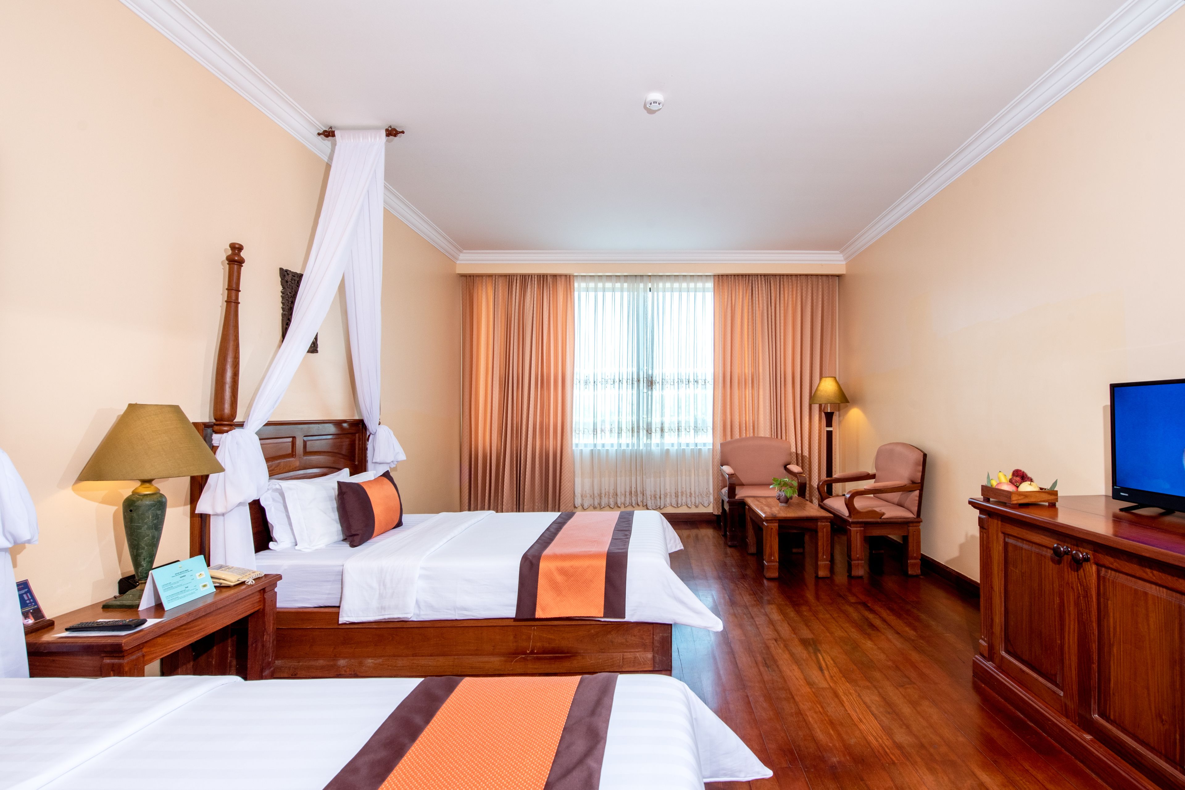 A hotel room with two beds, a TV, a desk, and a chair.