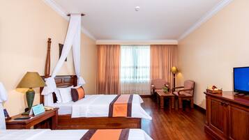 A hotel room with two beds, a TV, a desk, and a chair.