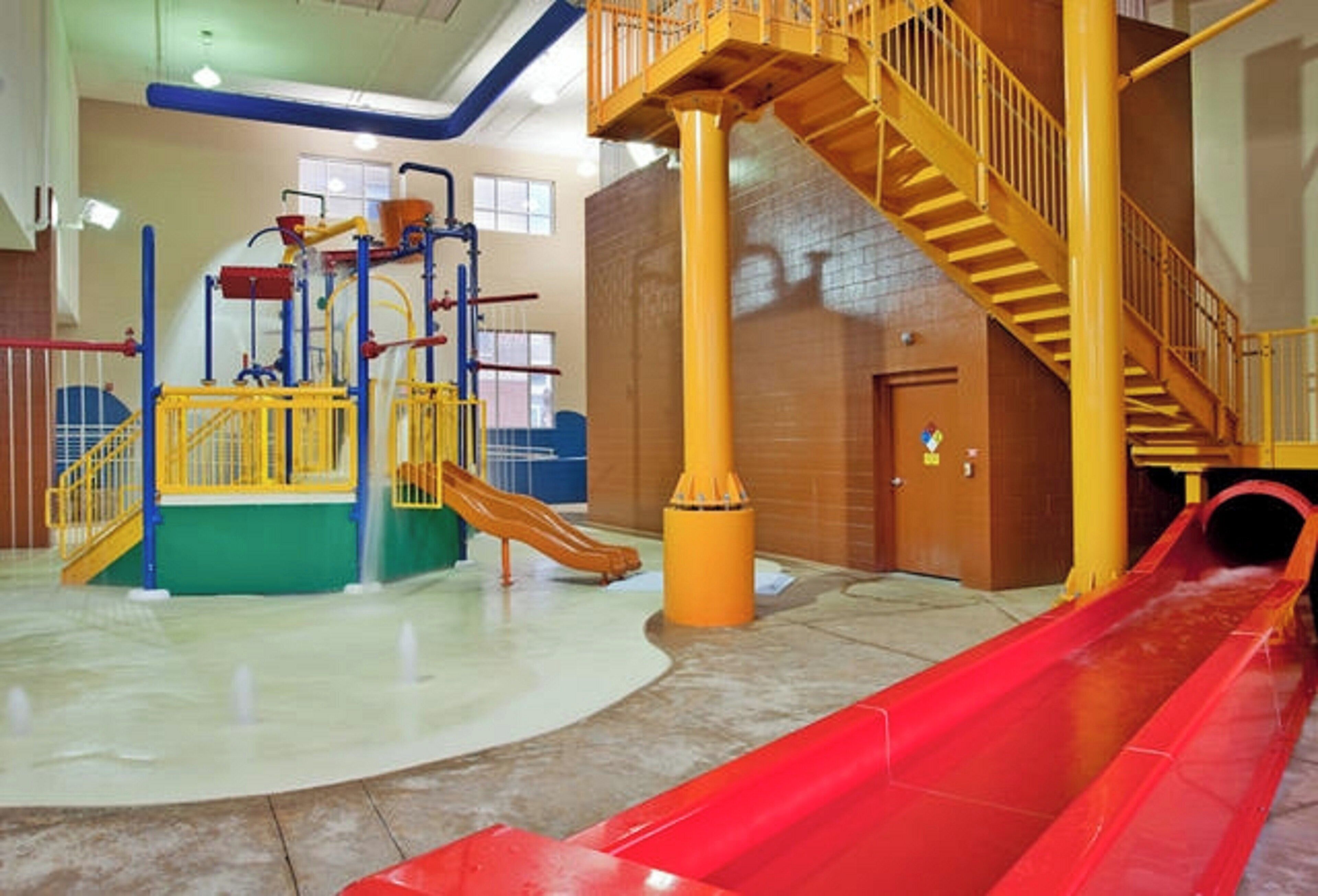 An indoor play area with a slide, climbing structures, and a staircase.
