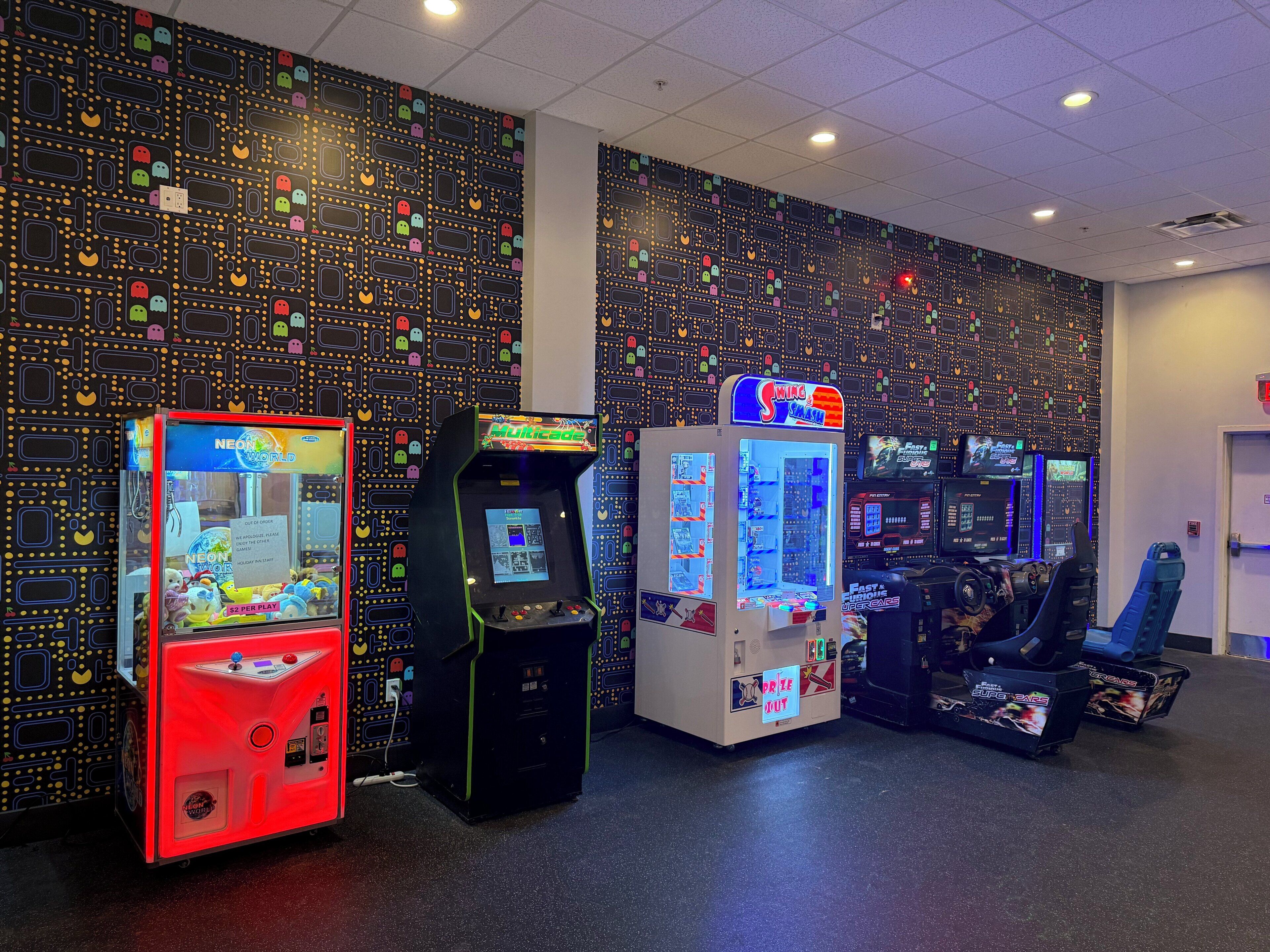 A row of arcade machines against a wall with a pattern of colorful dots and shapes.