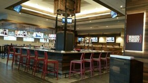 A restaurant with a bar area, multiple TVs mounted on the wall, and a sign for Burger Theory. - Holiday Inn Omaha Downtown - Waterpark by IHG (Omaha)