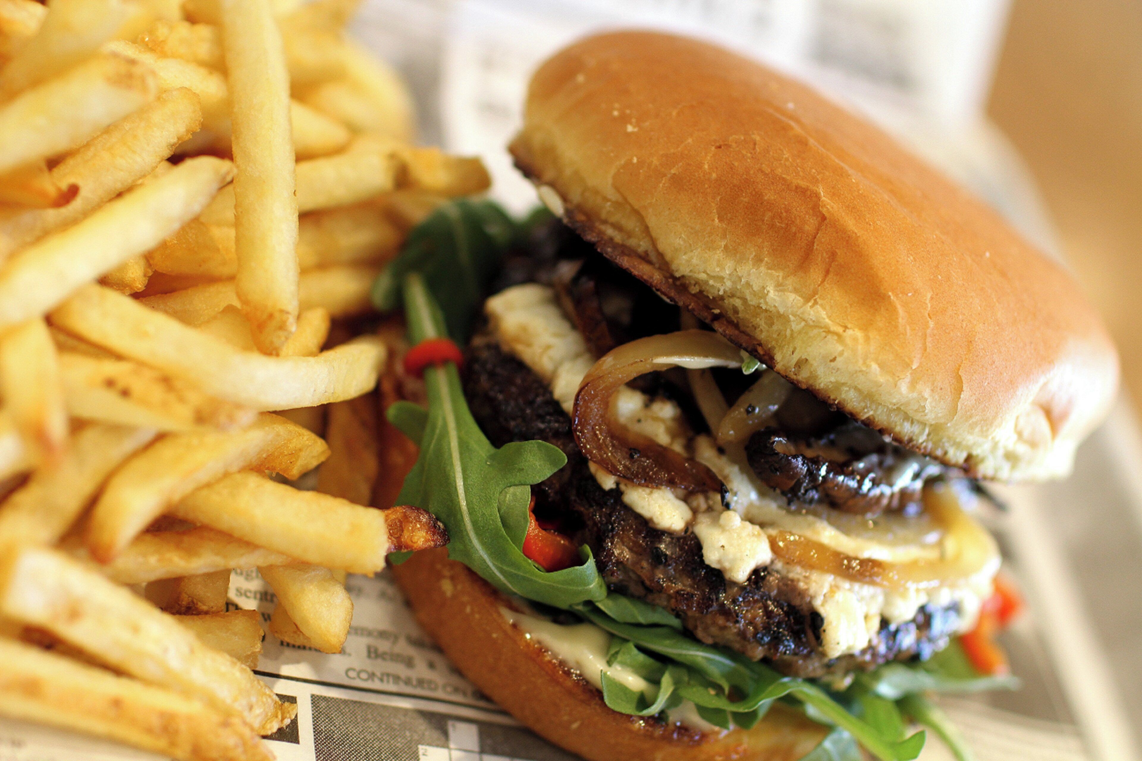 A sandwich with lettuce, a bun, and a side of fries.
