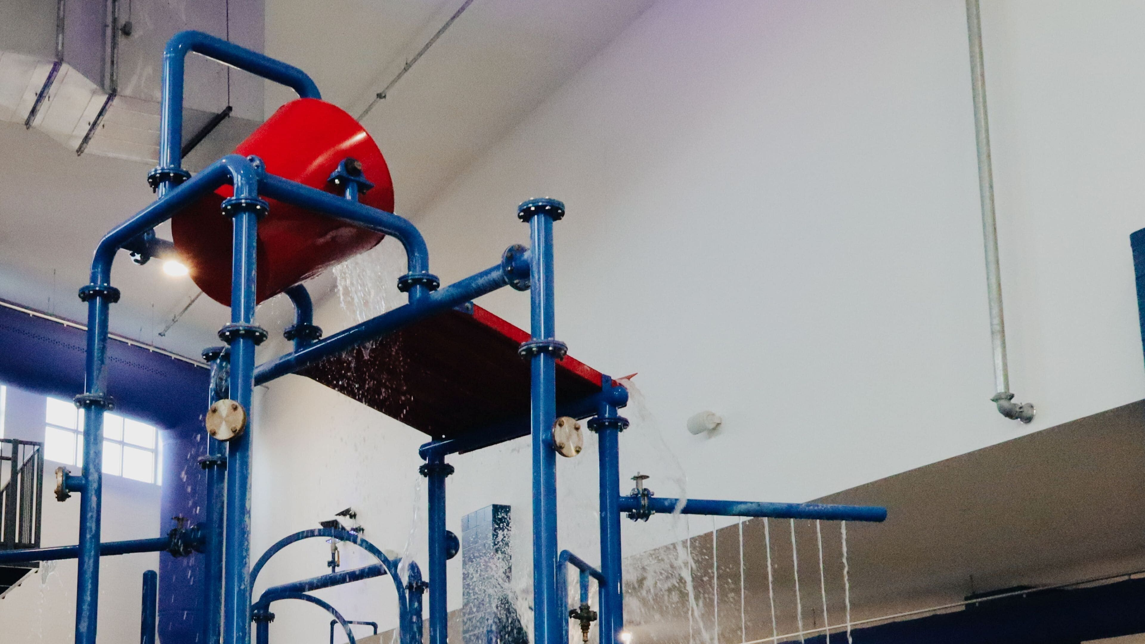 A water filtration system with pipes and a red tank.