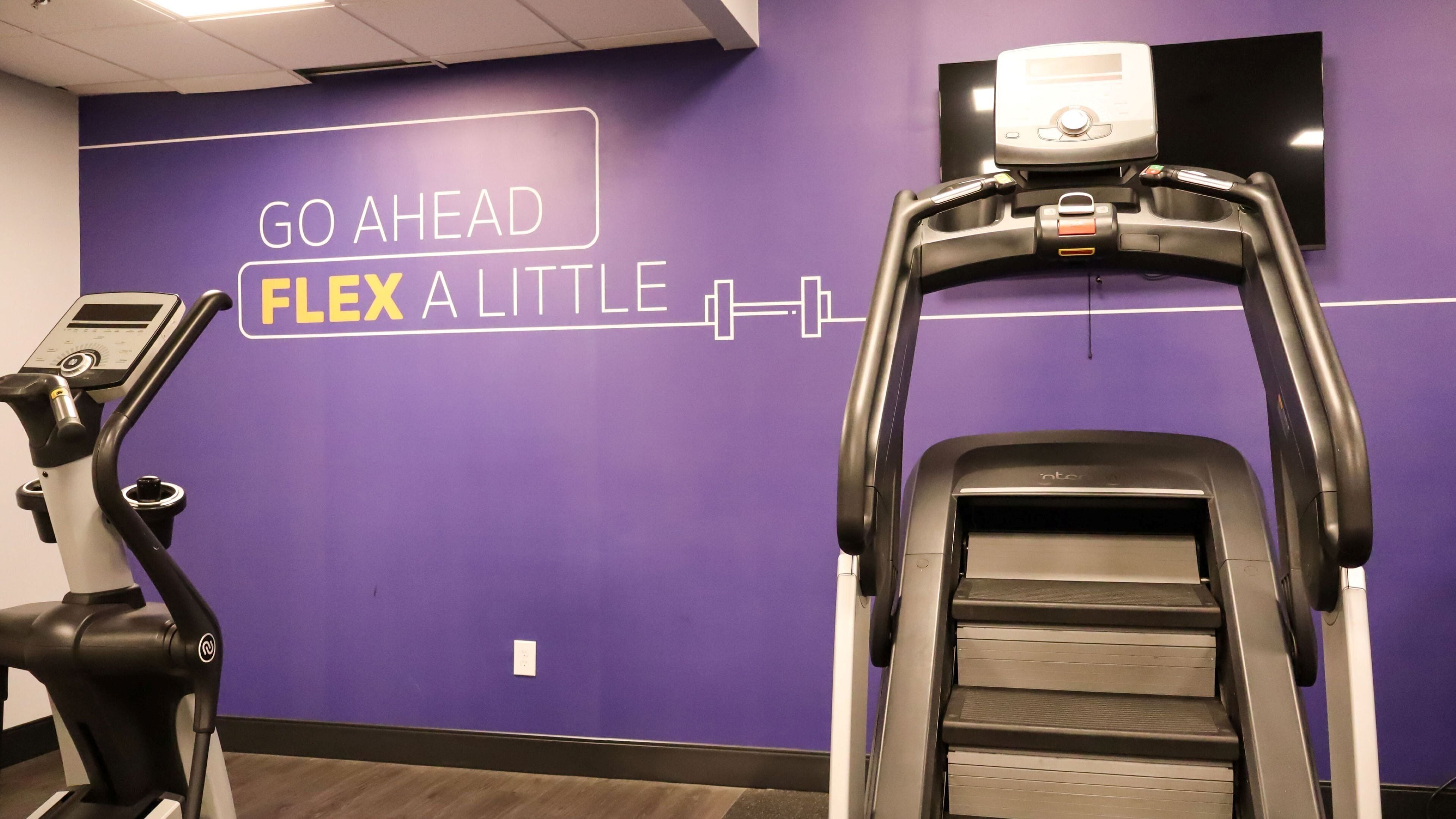 A gym with purple walls and treadmills.