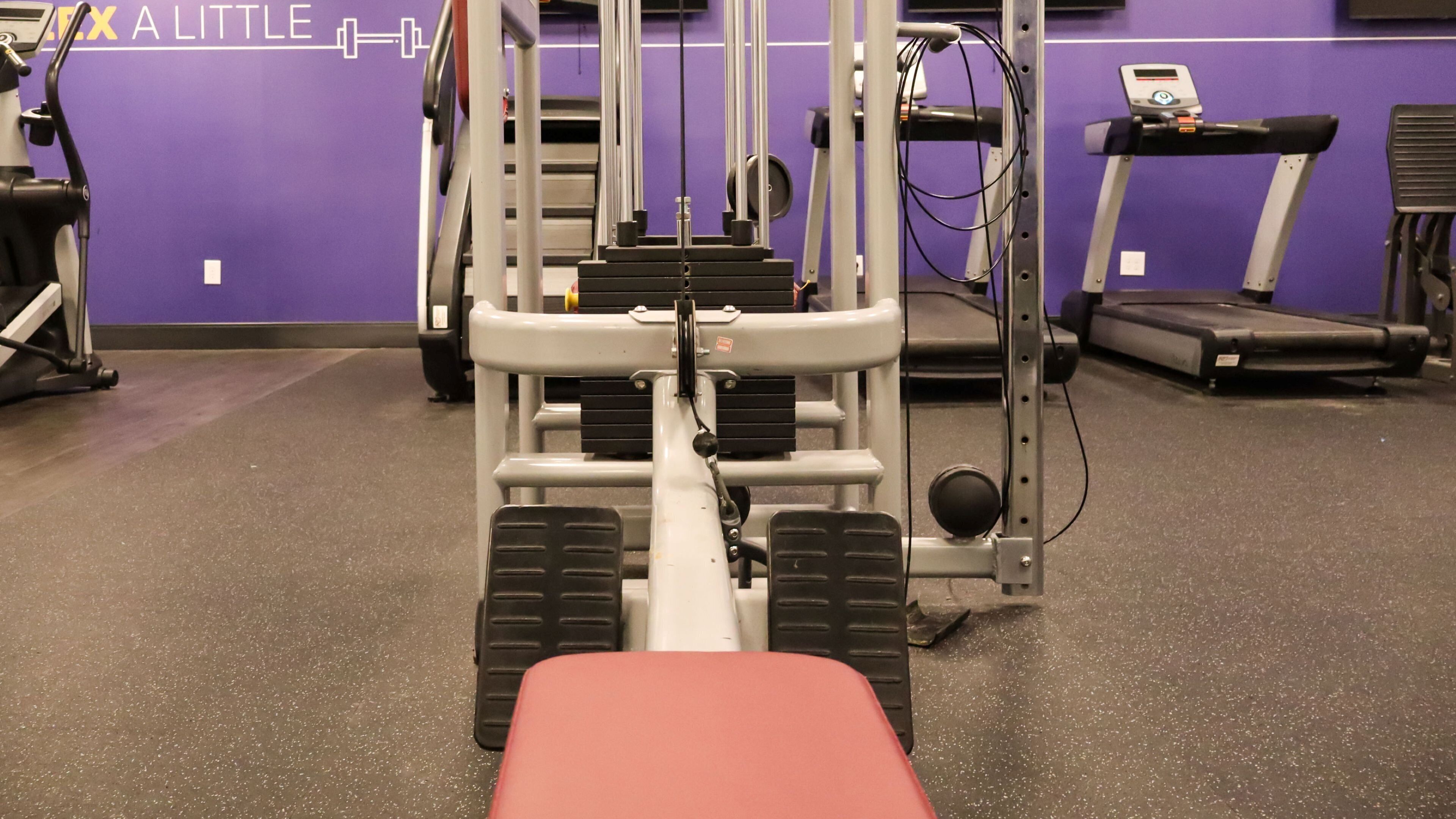 Un gimnasio con equipamiento de ejercicio, una cinta de correr y una pared con un cartel.