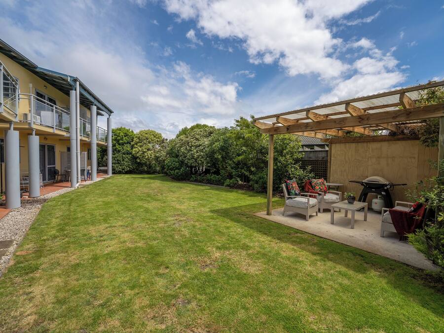 Un jardin avec un espace patio, du mobilier d’extérieur et une pergola.
