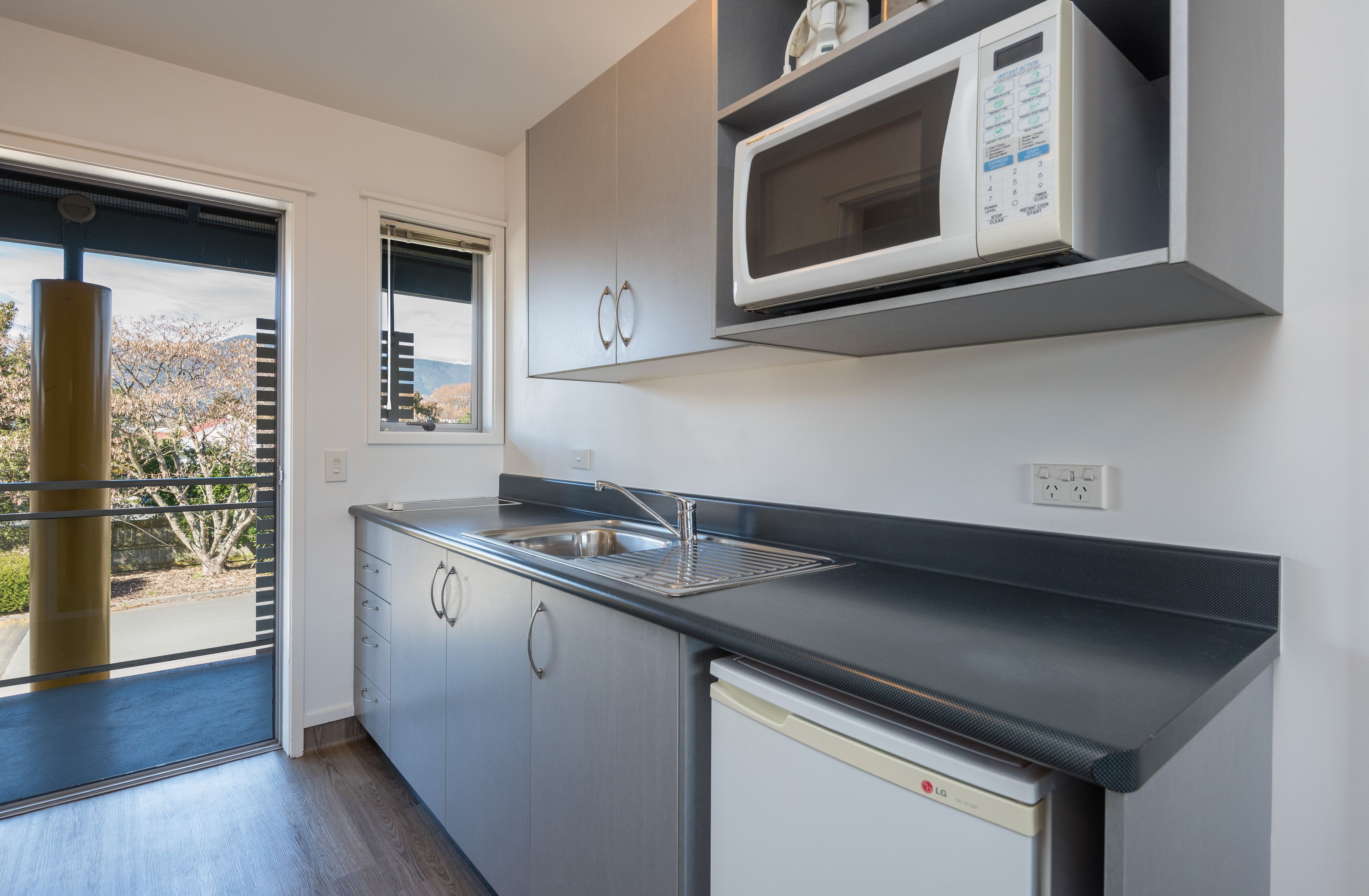 A modern kitchen with a built-in microwave, stainless steel sink, and a dishwasher.