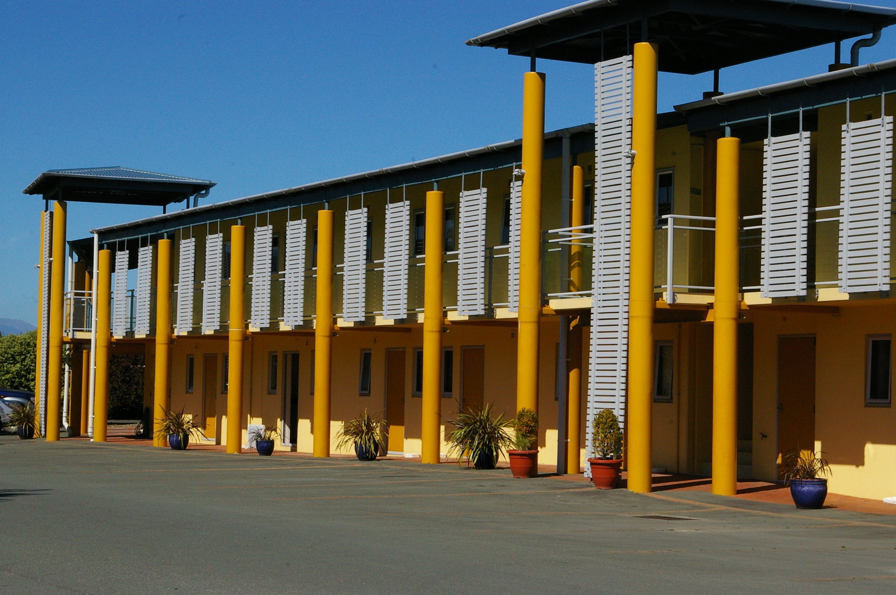 Un bâtiment jaune doté de nombreuses colonnes et d’une galerie couverte.