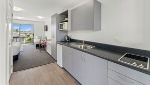 A modern kitchen with grey cabinets, a black countertop, and a built-in microwave.