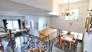 Un intérieur spacieux comprenant un escalier, un coin repas et un lustre.
