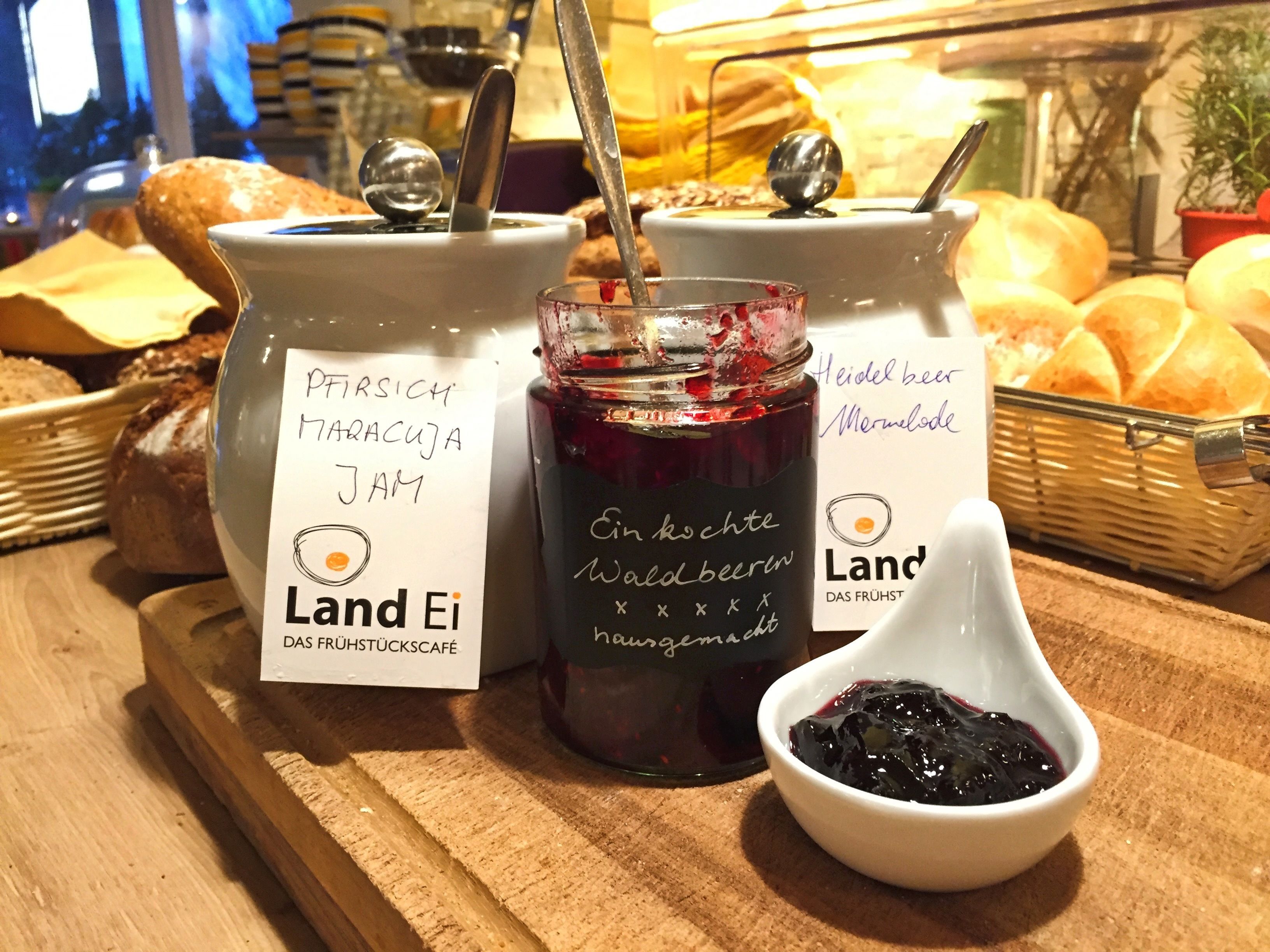 Jars of jam and bread on a wooden board.
