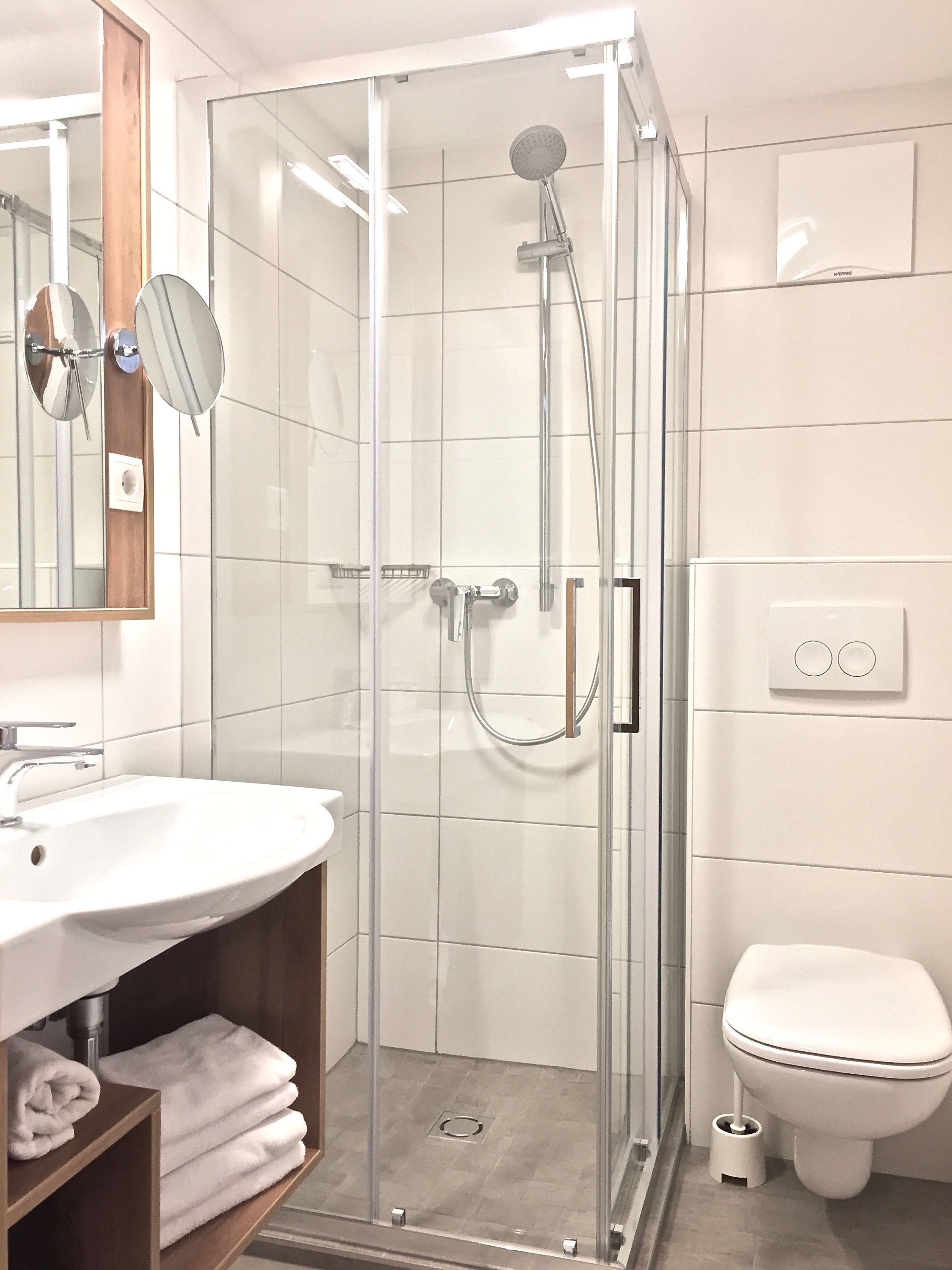 Ein modernes Badezimmer mit einer einteiligen Duschkabine, einem weißen Waschbecken und einer Toilette.