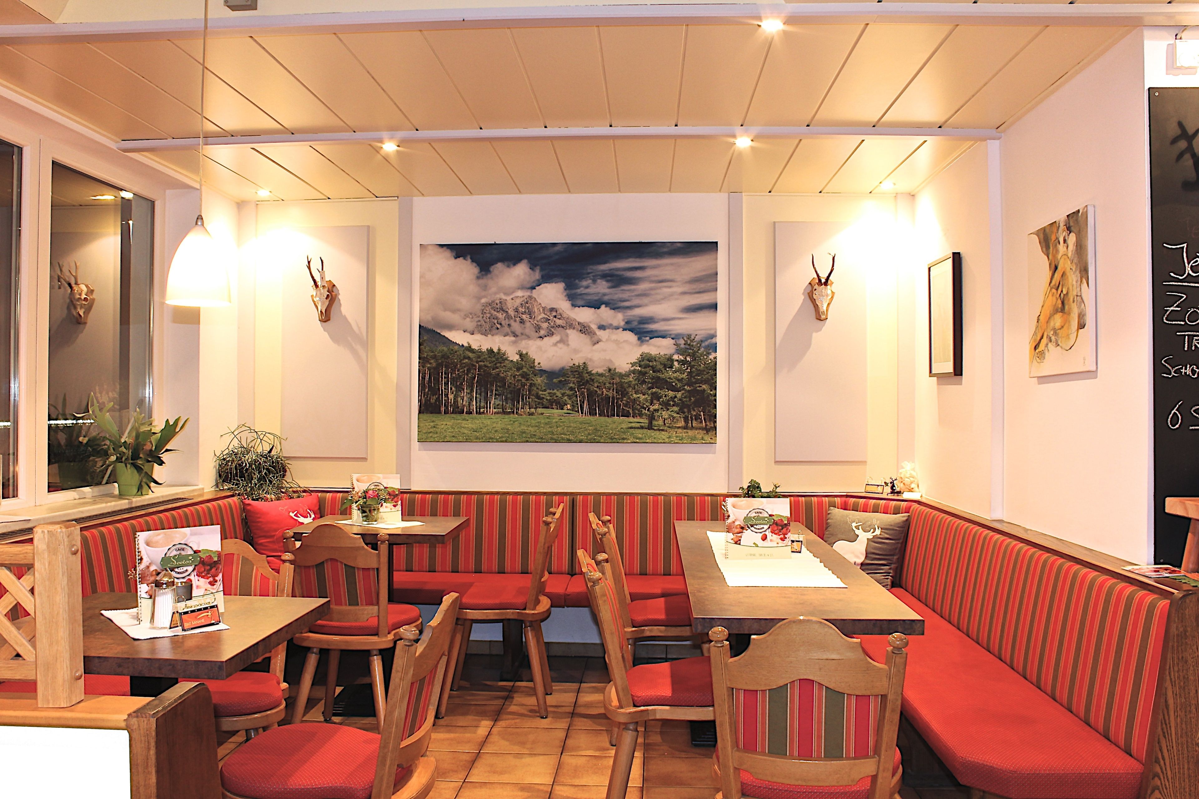 Een restaurant met houten tafels en banken, een groot berglandschap op de muur en een krijtmenu.