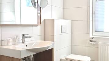 A modern bathroom with a white sink, mirror, and toilet.