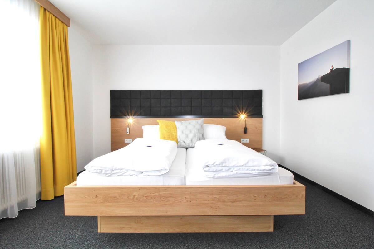 Una cama doble con estructura de madera, dos mesitas de noche, un cabecero y un cuadro colgado en la pared.