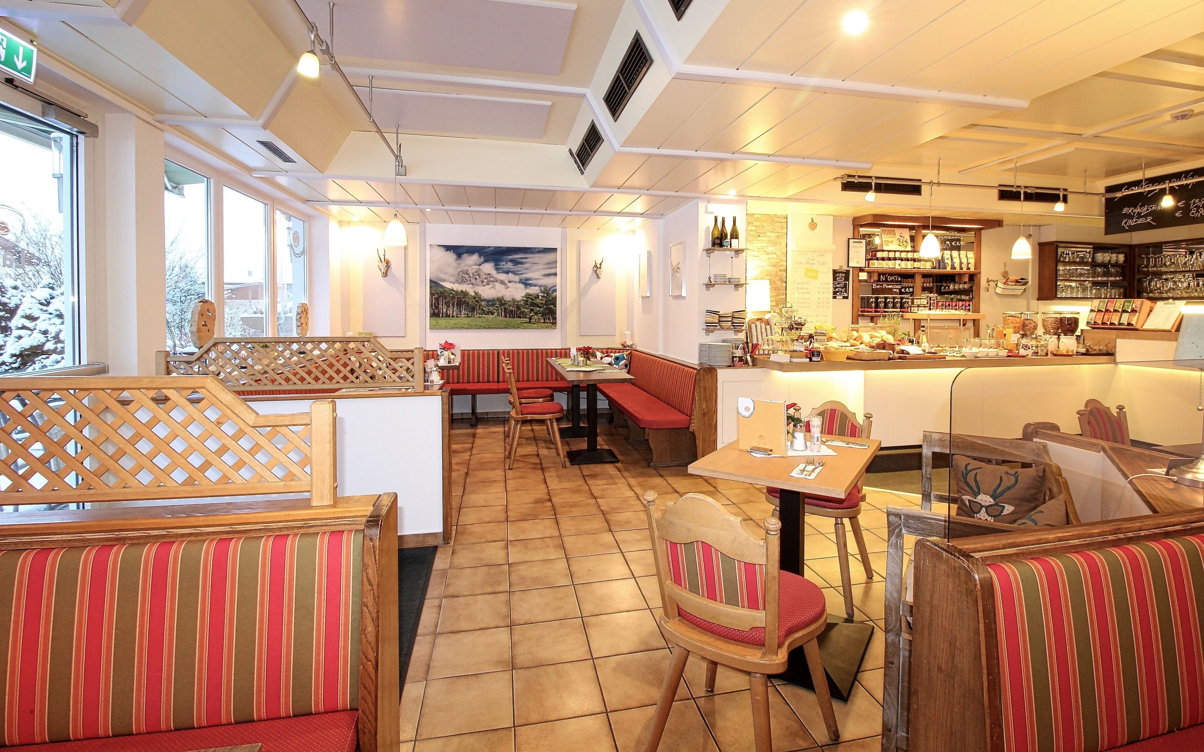 Un restaurante con mesas y cabinas, una zona de bar y vistas al exterior.