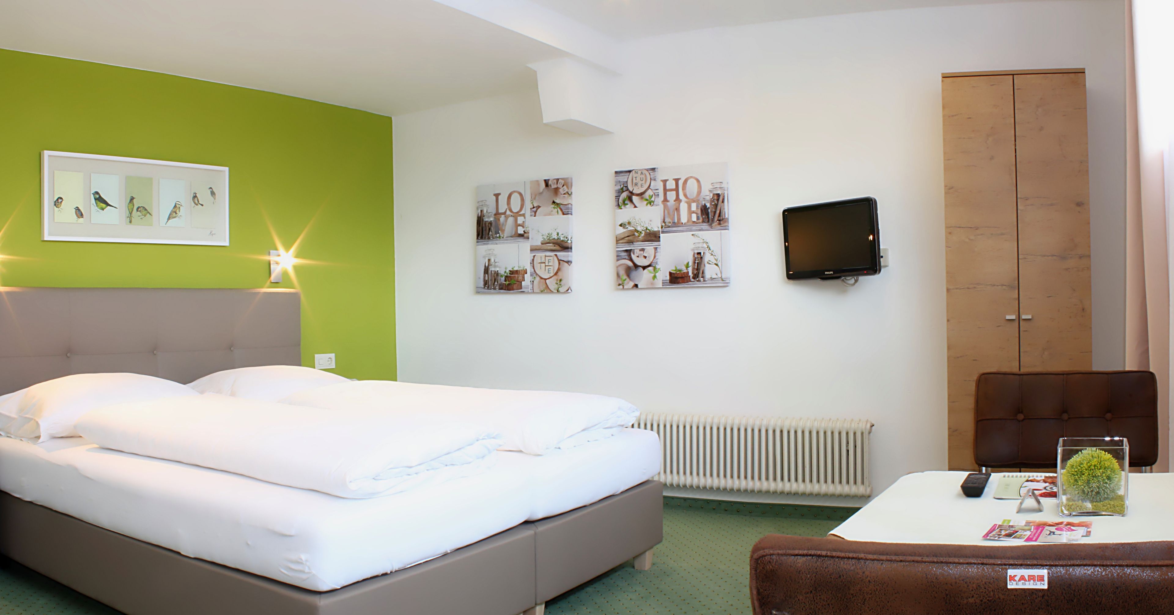 Una habitación de hotel con una cama, un escritorio, un televisor y un armario.