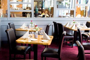 A restaurant interior with tables set for dining, chairs, and a view through the window. - Scotts Hotel Killarney (Killarney)